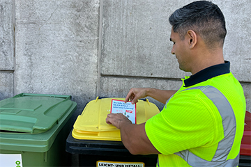 Mitarbeiter von Linz AG Abfall beim Anbringen eines Aufklebers für Fehleinwürfe auf der Tonne für Leichtverpackungen