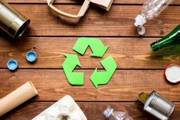 Recycling logo umgeben von etwaigen Abfällen.
