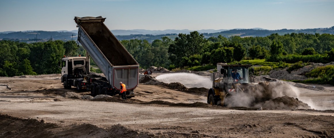 Divsere Bau-Fahrzeuge (Lastkraftwagen, Bagger, Traktor) verrichten ihre Arbeiten auf der Mülldeponie in Asten.