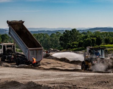 Divsere Bau-Fahrzeuge (Lastkraftwagen, Bagger, Traktor) verrichten ihre Arbeiten auf der Mülldeponie in Asten.
