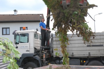 Ein Mitarbeiter von LINZ AG ABFALL hebt mit einem Kran Grünschnitt und Gartenabfälle in einen Container