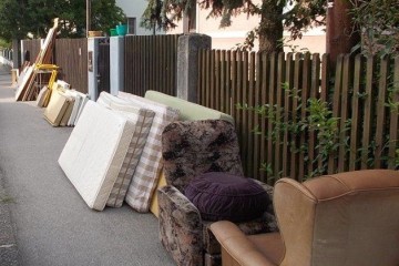 Sessel und Matratzen stehen am Gehsteig an eine Zaun gelehnt