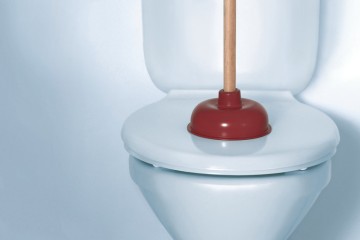 Bild von einer geschlossenen Toilette mit einer Saugglocke auf dem Klodeckel