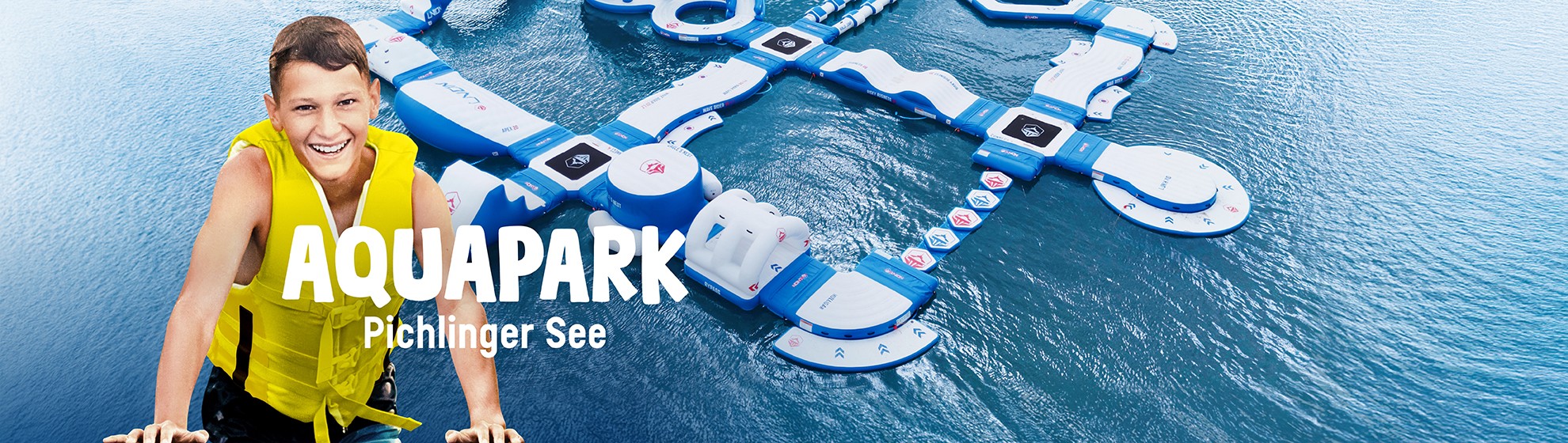 Auf dem Foto sieht man den Aquapark Pichlinger See im Wasser und einen Jungen mit einer Schwimmeweste an.
