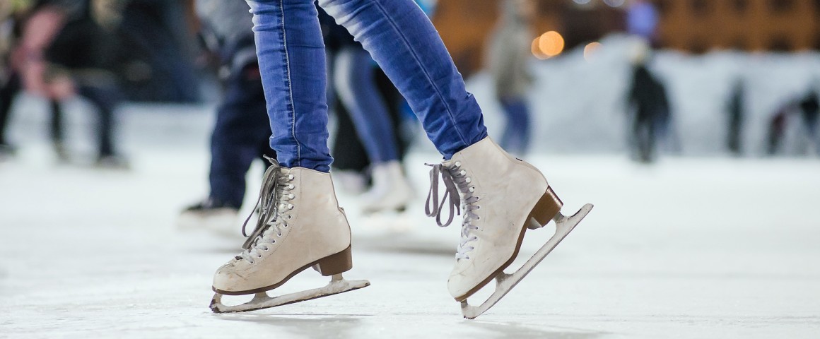 Frau mit Schlittschuhen auf der Eislauffläche