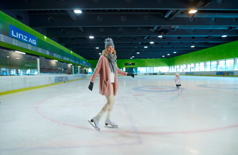 Frau fährt am Eis in der Eishalle im Parkbad