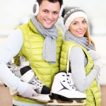 Ein Paar steht mit Schlittschuhen vor der Eislauffläche