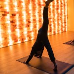 Eine Person macht eine Yogaposition auf einer Fitnessmatte vor einer Salzsteinwand. Eine Person macht eine Yogaposition auf einer Fitnessmatte vor einer Salzsteinwand.