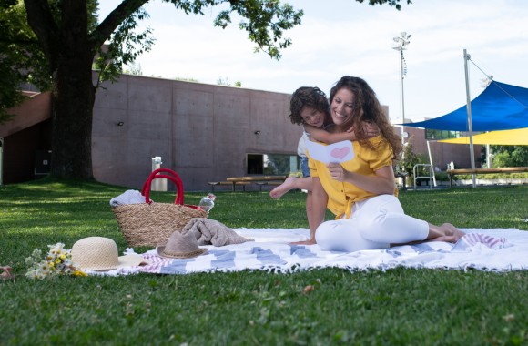 Nutter mit Kind sitzt auf einer Decke im Gras 