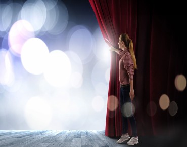 Mädchen öffnet den Vorhang auf einer Theaterbühne