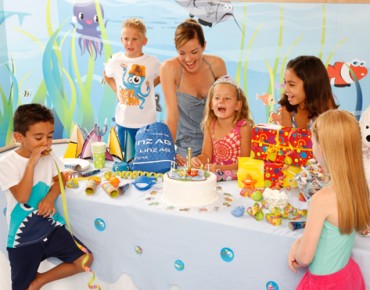 Kinder sitzen am Tisch und feiern Geburtstag