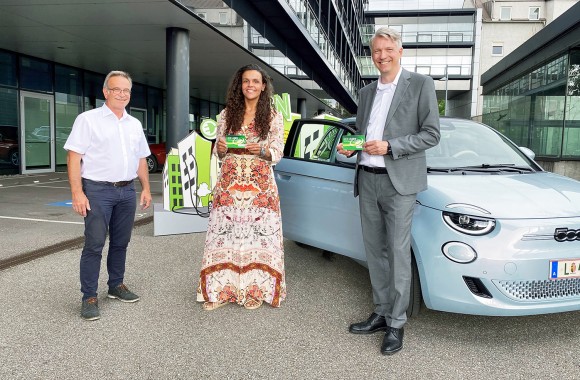 Drei Menschen (zwei Männer und eine Frau) stehen mit der LINZ AG Ladekarte vor einem blauen Auto.