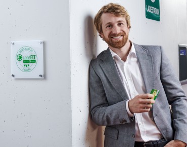 Mann lehnt mit Ladekarte in der Hand an der Wand in der Tiefgarage.