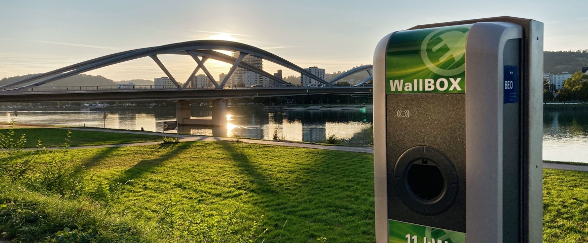 Ladsäule vor neuer Donaubrücke im abendlichen Gegenlicht.