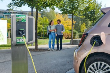 Auto an der Ladesäule, Pärchen im Hintergrund.