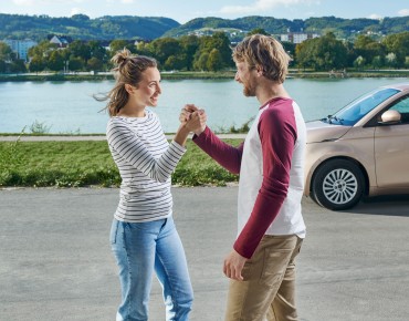 Pärchen an der Donau vor dem Auto.