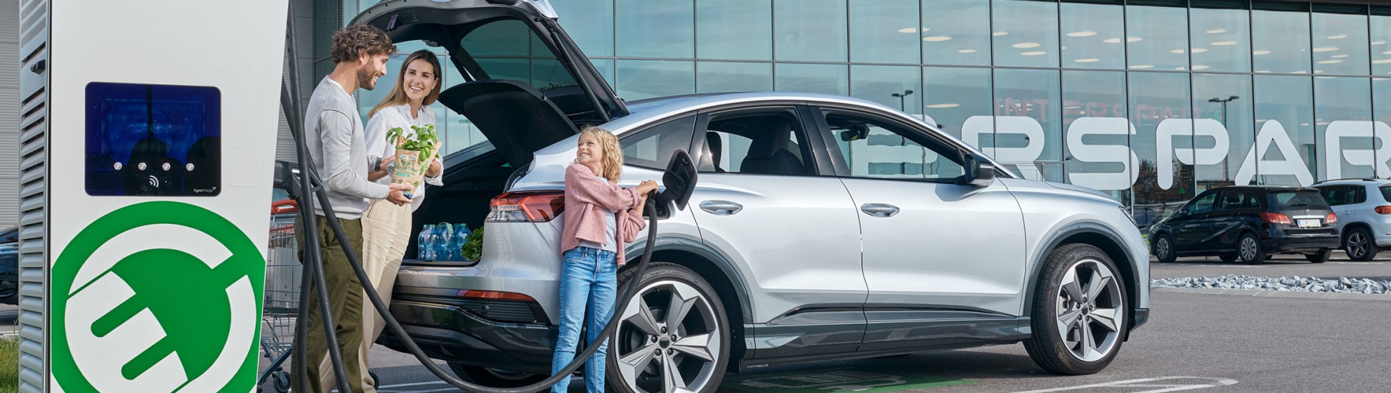 Familie belädt das Auto auf dem Supermarktparkplatz.