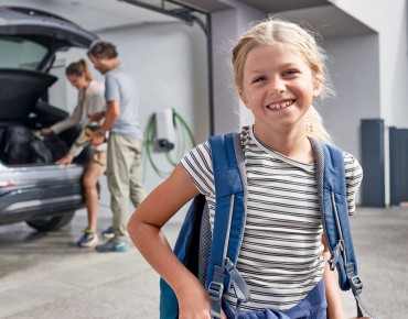 Kind vor E-Auto in der Garage.