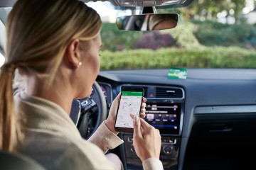 Frau sitzt mit Ihrem Smartphone im Auto
