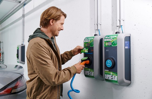 Ein Mann steckt das Ladekabel seines E-Autos an der WallBOX an.