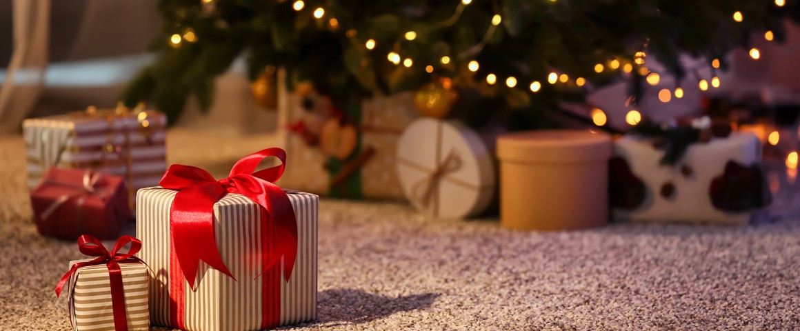 Zwei Geschenkspäcken vor einem geschmückten Weihnachtsbaum