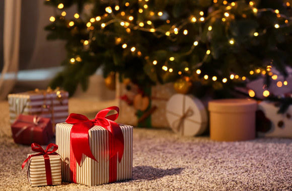 Zwei Geschenkspäcken vor einem geschmückten Weihnachtsbaum