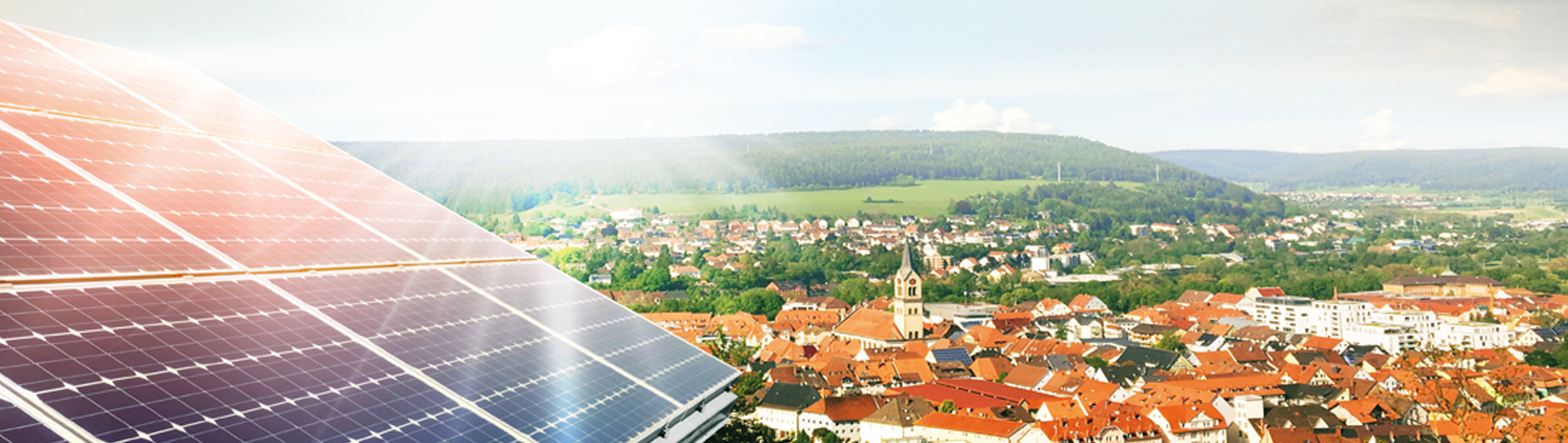 Luftaufnahme einer Gemeinde, im Vordergrund ist eine Photovoltaikfläche zu sehen