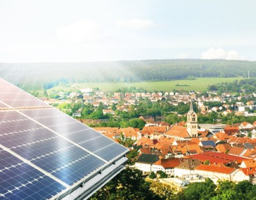 Luftaufnahme einer Gemeinde, im Vordergrund ist eine Photovoltaikfläche zu sehen