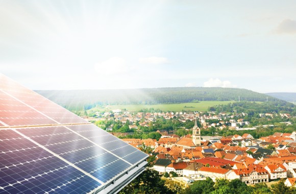 Luftaufnahme einer Gemeinde, im Vordergrund ist eine Photovoltaikfläche zu sehen