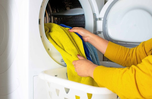 Eine Frau räumt Wäsche aus der Waschmaschine oder dem Trockner