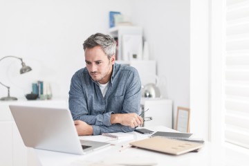 Mann zuhause vor dem Laptop bei der Arbeit