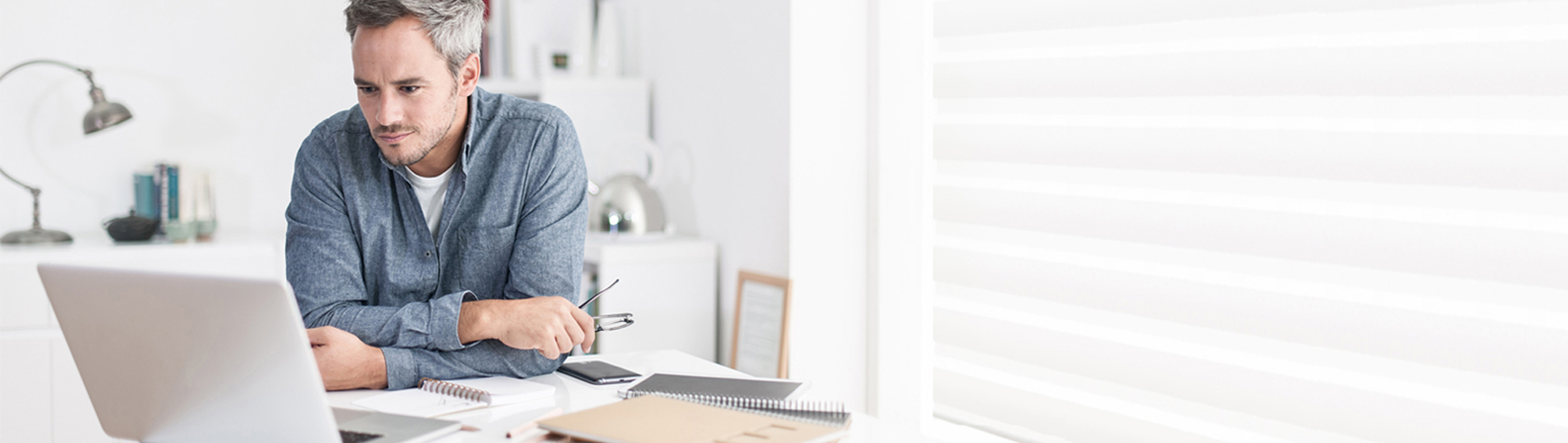 Mann zuhause vor dem Laptop bei der Arbeit