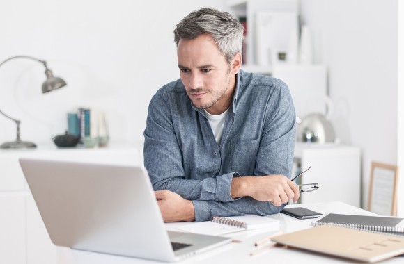 Mann zuhause vor dem Laptop bei der Arbeit