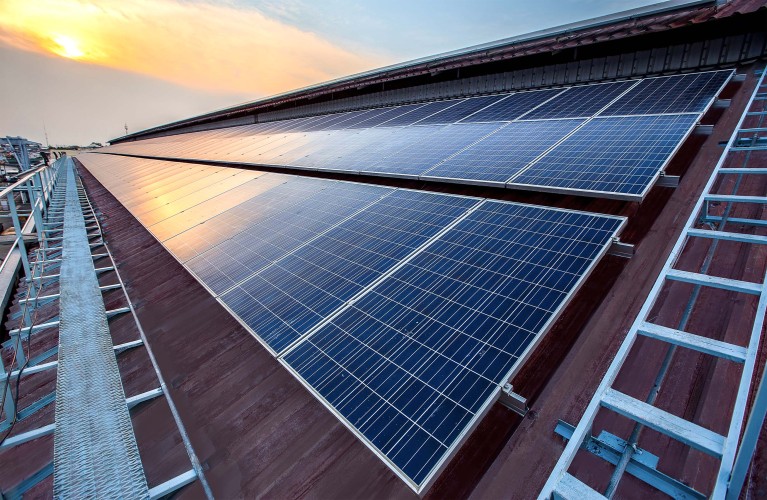 Nahaufnahme einer Photovoltaikanlage auf dem Dach eines Unternehmens bei Sonnenuntergang