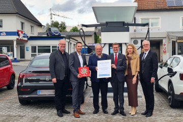 Personen der Linz-Energieservice GmbH und der Messe Mühlviertel stehen am Stadtplatz Freistadt beim neuen Ladepark und halten ein Zertifikat in Händen