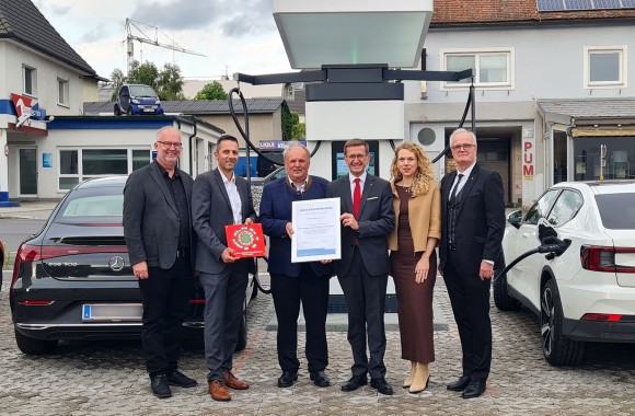 Personen der Linz-Energieservice GmbH und der Messe Mühlviertel stehen am Stadtplatz Freistadt beim neuen Ladepark und halten ein Zertifikat in Händen
