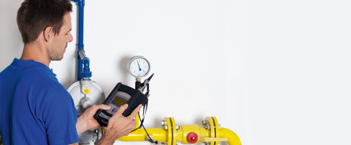 Ein Techniker steht mit Messgerät vor einer Gasanlage und überprüft die Funktionalität.