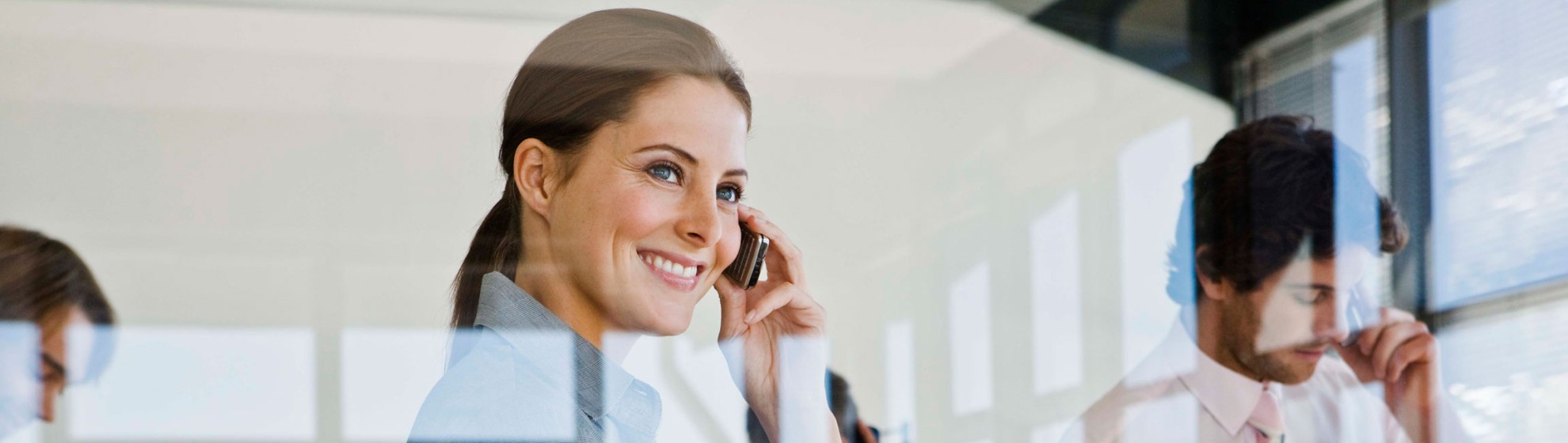 Blick durch eine Fensterscheibe auf eine telefonierende Businessdame.