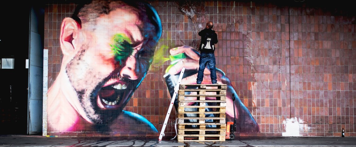 Graffitikünstler besprüht Wand im Linzer Hafen mit einem riesigen Graffiti, das einen Mann zeigt, der sich selber in die Augen sprayt. Das Werk heißt "Paint It Black 2015" und stammt vom Künstler SHED.