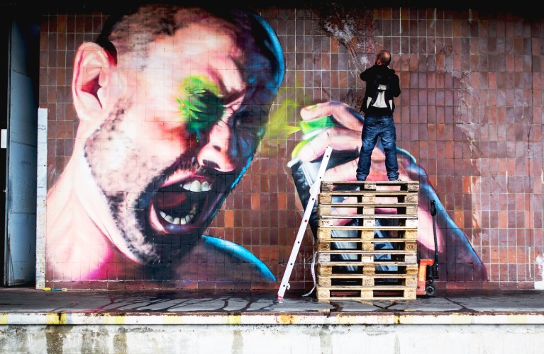 Graffitikünstler besprüht Wand im Linzer Hafen mit einem riesigen Graffiti, das einen Mann zeigt, der sich selber in die Augen sprayt. Das Werk heißt "Paint It Black 2015" und stammt vom Künstler SHED.