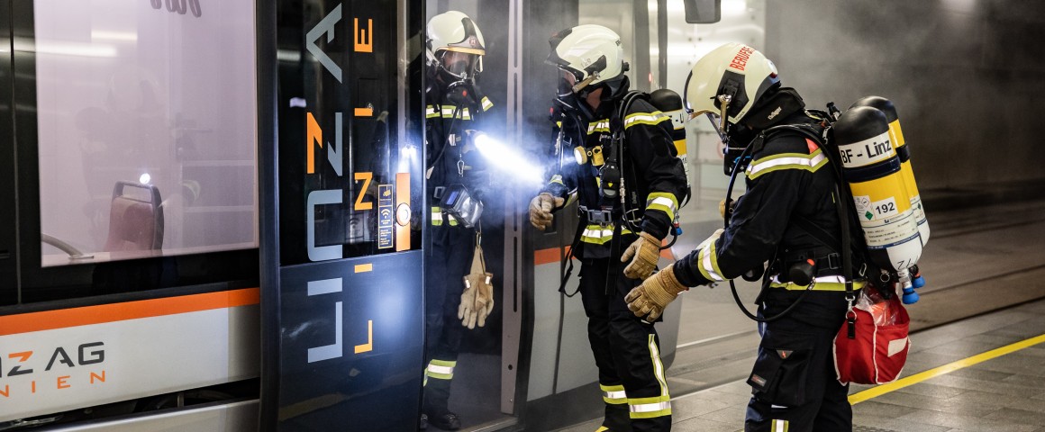Feuerwehrmänner löschen eine verrauchte Straßenbahn im Tunnel
