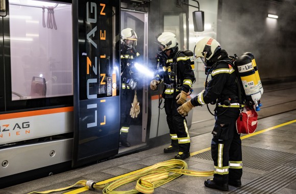 Feuerwehrmänner löschen eine verrauchte Straßenbahn im Tunnel