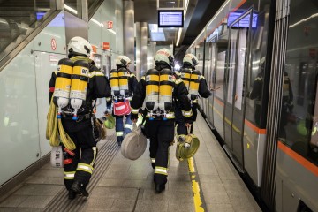 Feuerwehrmänner mit Atemschutz neben einer Straßenbahn