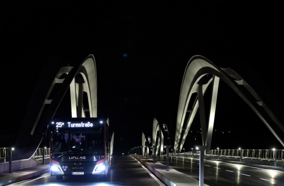 Abbildung von einem LINZ AG Linien Bus, welcher zum Ersten Mal über die neue Eisenbahnbrücke fährt.