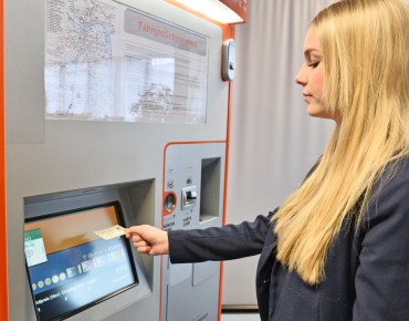 Einfache Bedienweise zeichnet die Fahrscheinautomaten aus. Eine Frau steht vor einem Fahrscheinautomat.