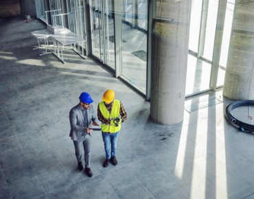 ein Bauleiter und ein Bauarbeiter stehen auf einer Baustelle aus der Vogelperspektive