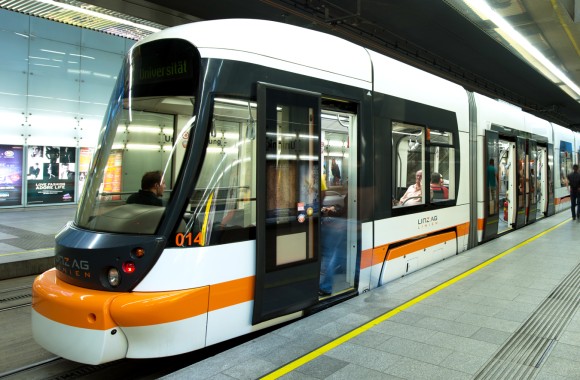 Straßenbahn fährt durch Tunnel und bei Haltestelle vorbei