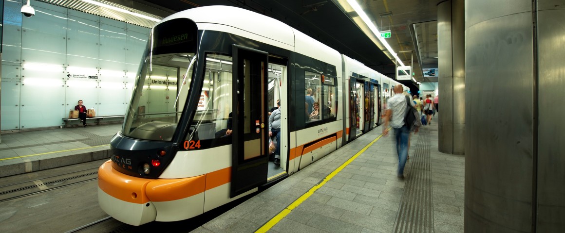 Straßenbahn fährt durch Tunnel und bei Haltestelle vorbei