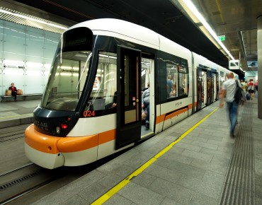 Straßenbahn fährt durch Tunnel und bei Haltestelle vorbei