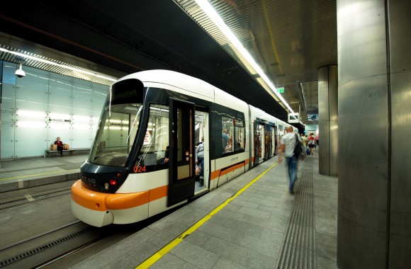 Straßenbahn fährt durch Tunnel und bei Haltestelle vorbei